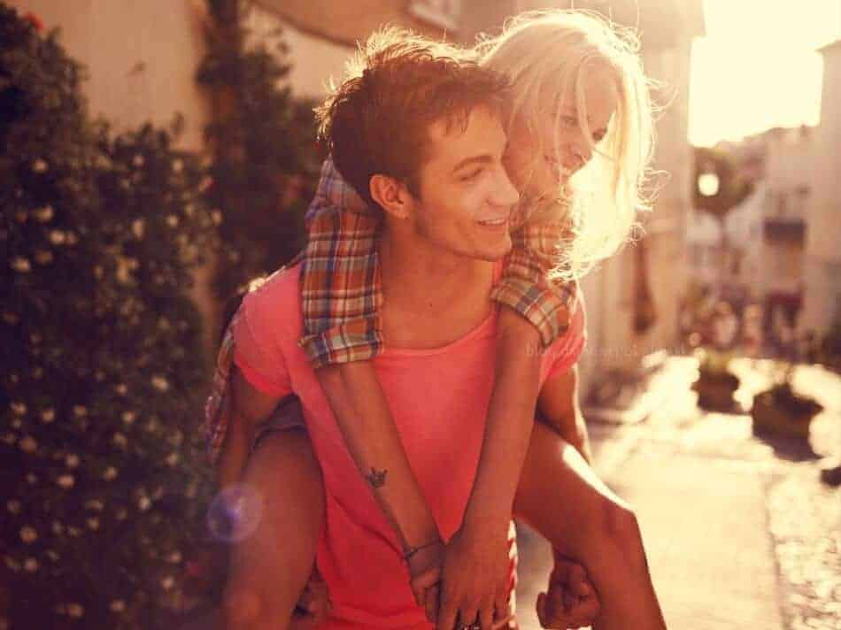 Casal jovem se divertindo com ela sendo carregada nas costas por ele