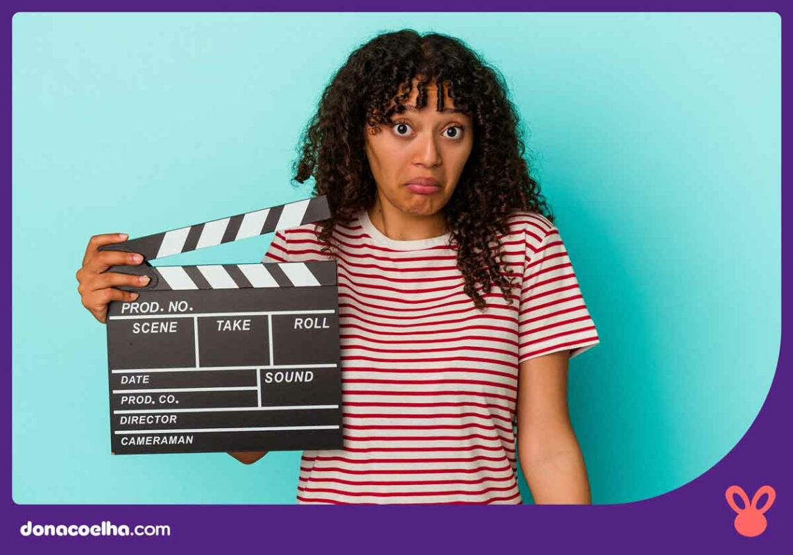 Pessoa com rosto de dúvida segurando uma claquete de cinema