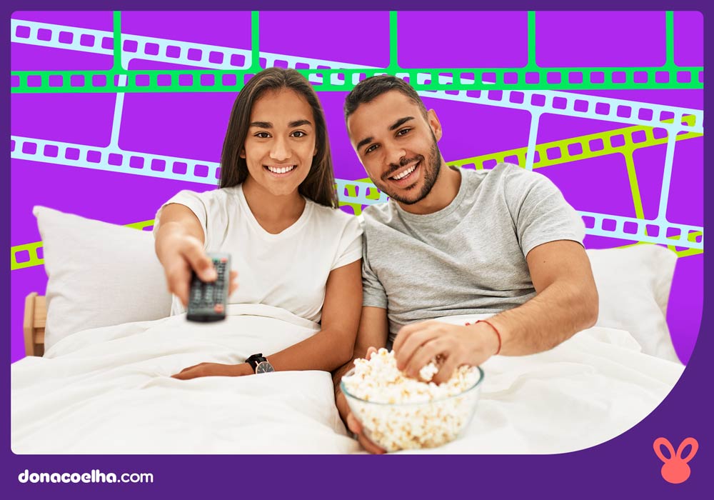 casal sentado na cama para assistir filme erótico
